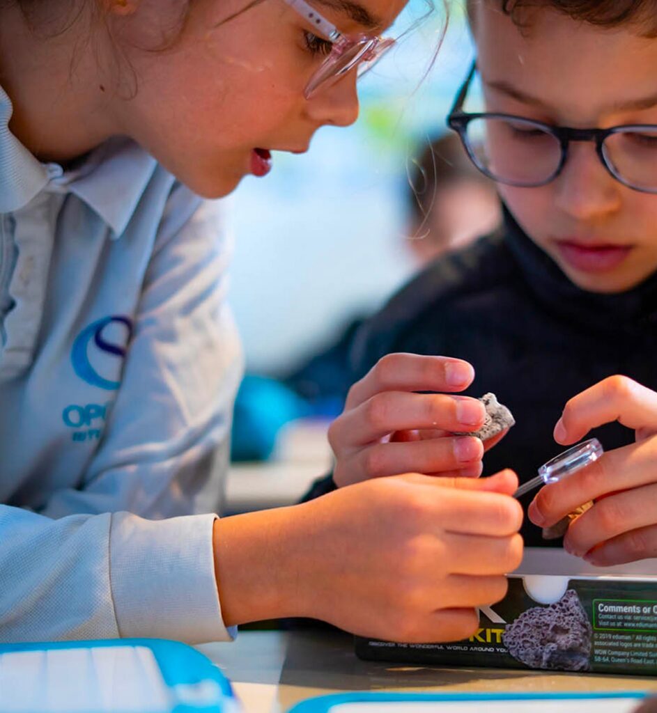 Élèves de primaire observant des minéraux en cours de sciences à Open Sky International